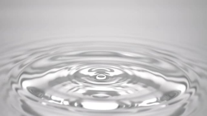 水滴落在灰色流体表面上，形成水环