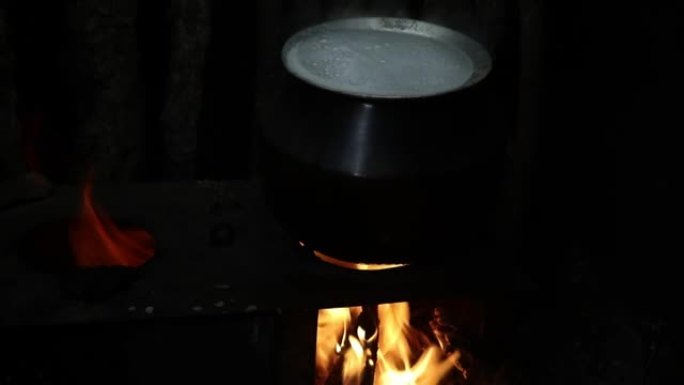 传统的煮饭方式，柴火炉上的电饭锅，顶部有沸腾的气泡
