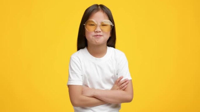 有趣的韩国小女孩戴着墨镜在黄色背景上摆姿势