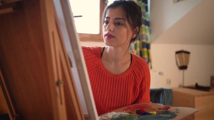 有天赋的女艺术家在家在画布上绘画时享受创作时间