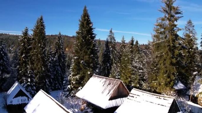 山里白雪覆盖的小屋的鸟瞰图。雪白的冬天风景。美丽的山间小屋或小屋在冬季森林中被雪覆盖。