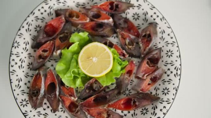一盘海鲜，美味的新鲜鱼子酱切片鱼放在盘子上，生菜和柠檬放在白色桌布上，特写镜头