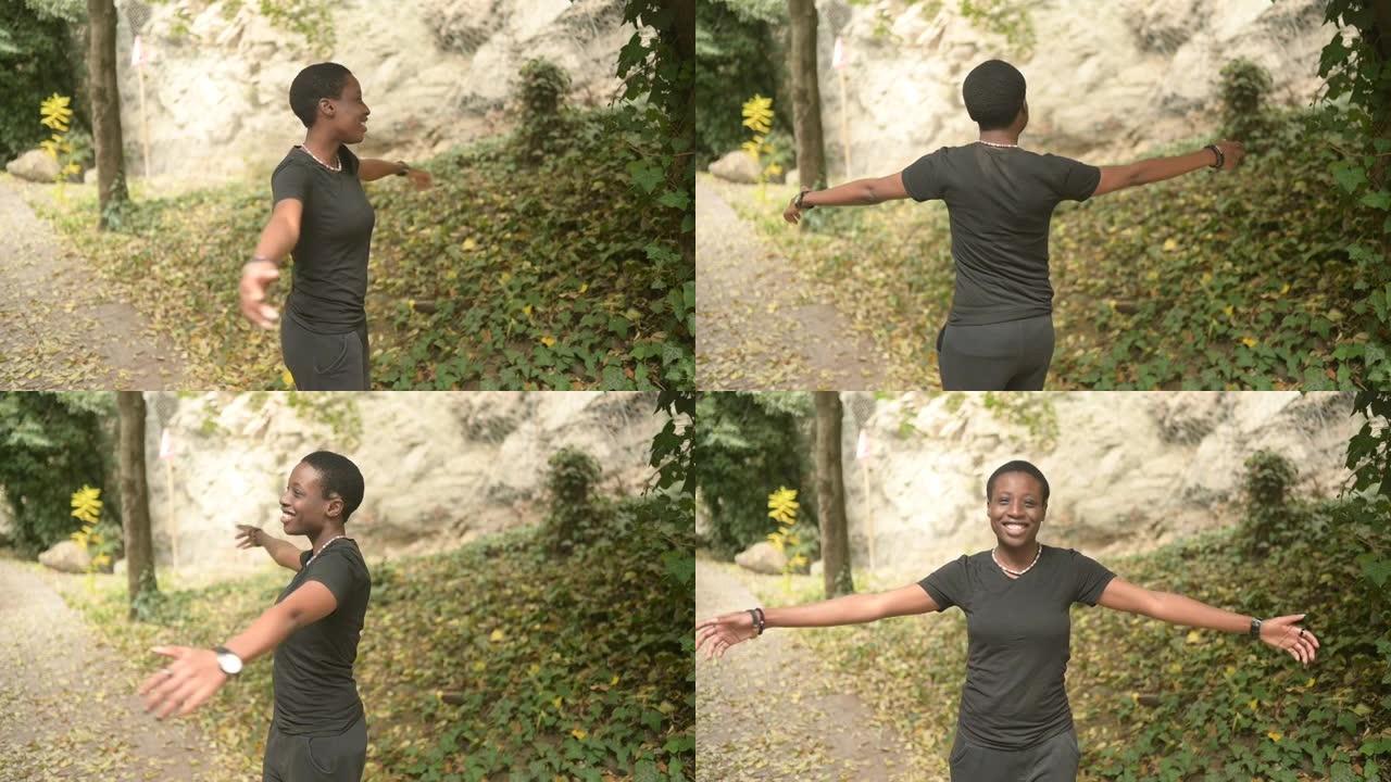 迷人的快乐微笑年轻的自然美女短发非洲女人穿着全黑旋风，在自然绿色夏季公园跳舞。多样性概念。