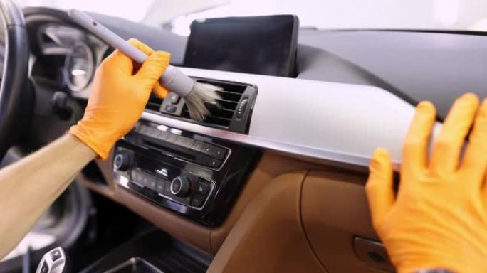 男子手持橙色防护手套中的灰色腮红，清洁汽车4k电影中的通风系统