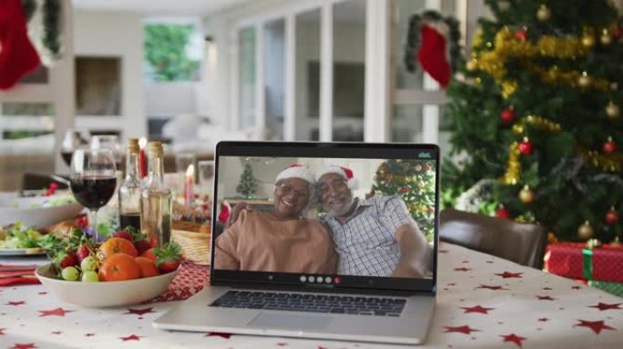 躺在圣诞节桌上的笔记本电脑上的快乐非洲裔美国祖父母