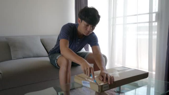 亚洲男子打开一个装有未完成桌子的盒子