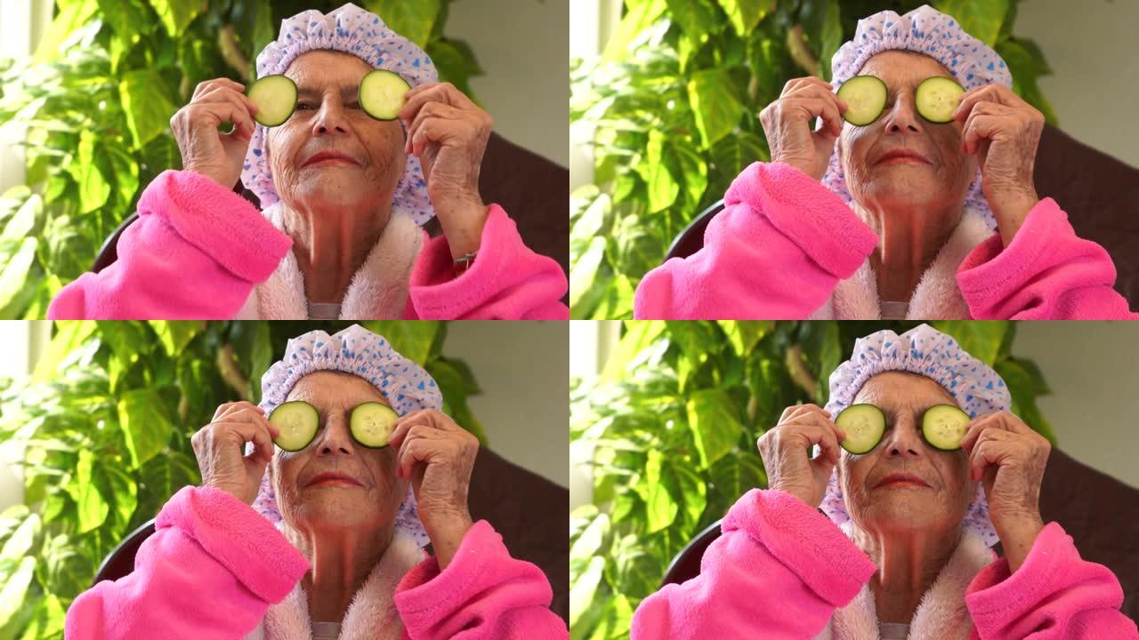 美丽的白人拉丁祖母拿着一片黄瓜在脸上戴口罩。