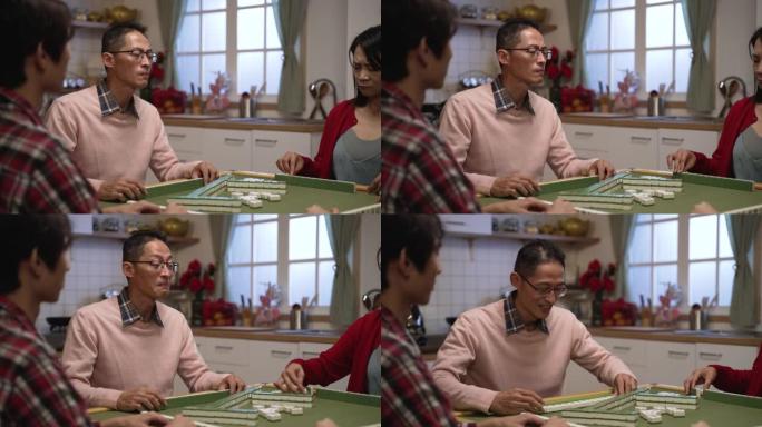 选择性聚焦的亚洲男性父亲在淡红色的眼睛手势，他的妻子想要瓷砖和赢在麻将游戏在中国除夕在家里