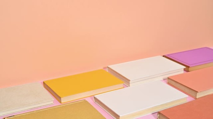各种颜色的精装书出现在粉红色橙色主题的底部。停止运动