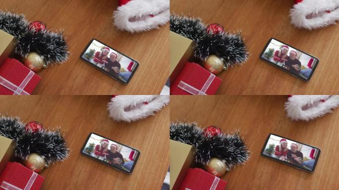 微笑的白人夫妇戴着圣诞老人的帽子，在智能手机上播放圣诞节视频通话
