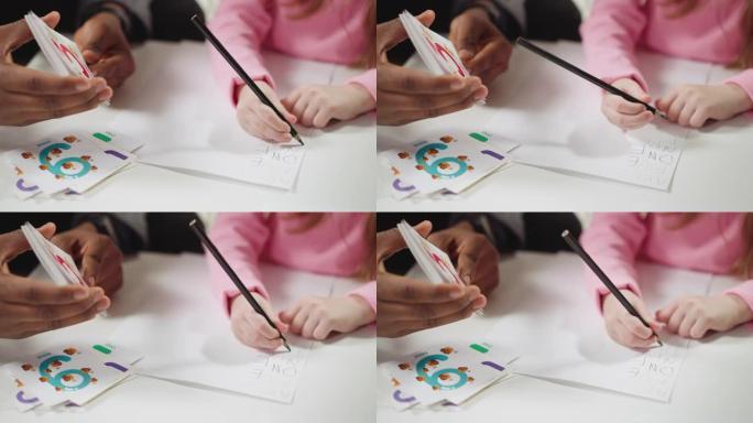 导师展示卡片，女孩用英语写数字名字