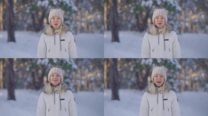 穿着暖和的冬装的可爱女孩的肖像看着相机，带着惊喜和惊喜。年轻女子在白雪皑皑的森林模糊背景下在户外摆姿