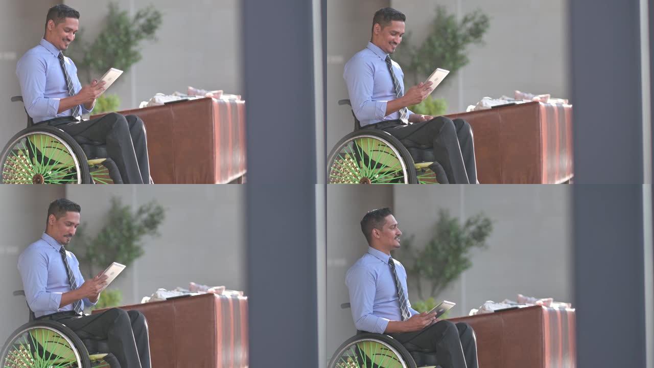 在休息区使用笔记本电脑微笑禁用轮椅上的亚洲印度男性白领