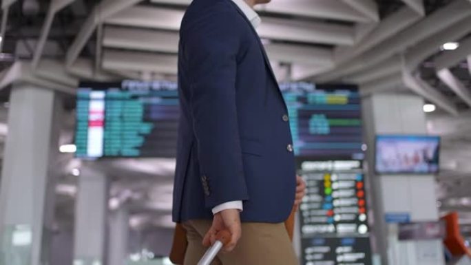 商人旅客在现代机场航站楼拉行李箱，手提包行李。。年轻的旅行者男子背着肩包和随身行李在机场散步，特写镜