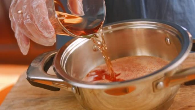 将酒醋从透明玻璃杯中倒入辣椒酱的成分中。自制辣椒酱。4k视频