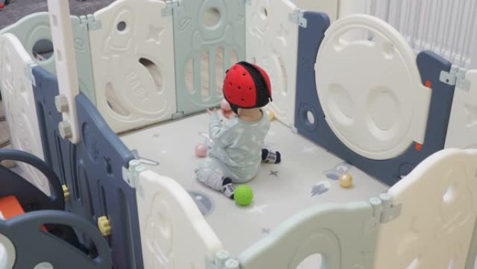 可爱的婴儿幼儿在婴儿和幼儿的可折叠婴儿游戏围栏中玩球坑，儿童活动中心安全游戏场让儿童远离伤害。戴着安