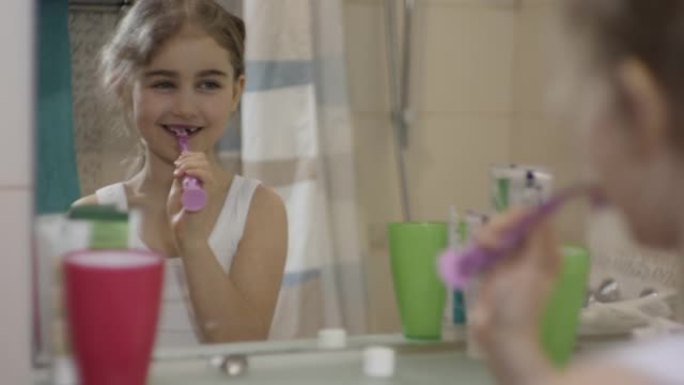 特写肖像年轻小女孩在浴室里用牙刷跳舞唱歌看着镜子反射。日常口腔卫生。快乐肖像高加索无牙儿童在浴室跳舞