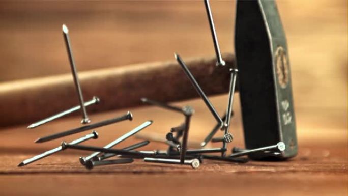 钉子用锤子落在桌子上。拍摄的是每秒1000帧的慢动作。