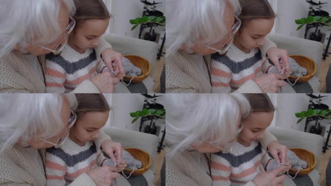 老年妇女教小女孩如何用辐条编织羊毛线