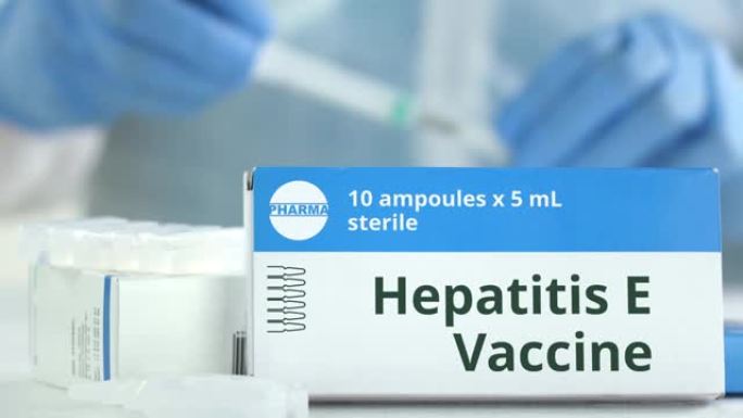 工作实验室助理或医生附近的桌子上有戊型肝炎疫苗的安瓿，盒子上有虚构的徽标