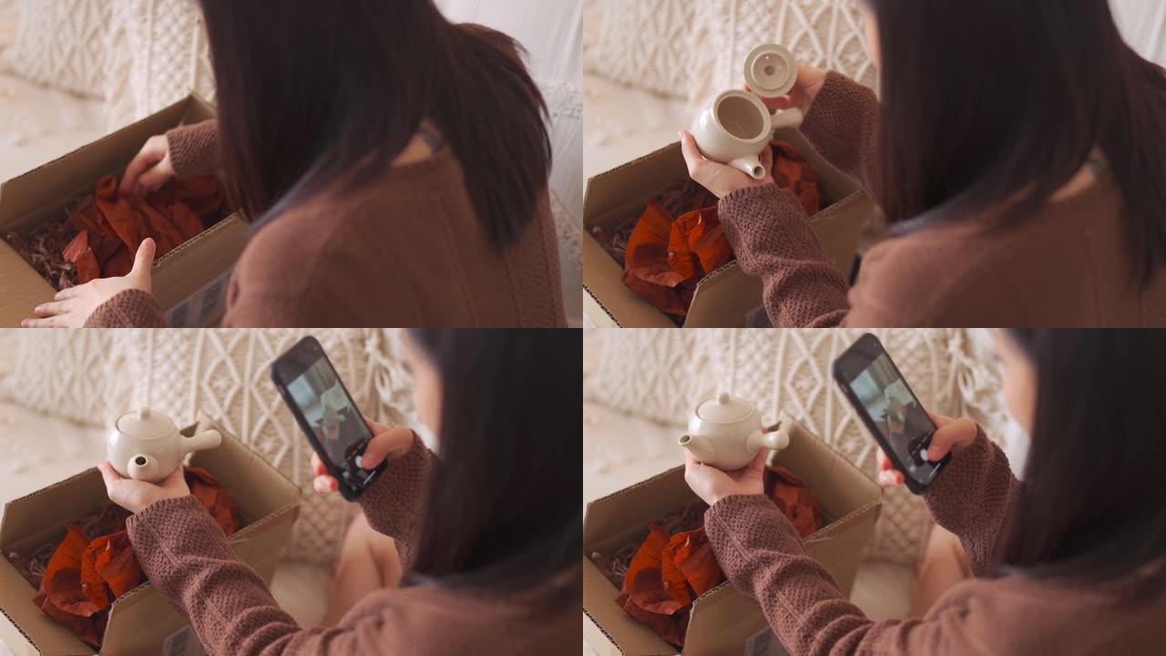 快乐的亚洲中国女人在客厅网上购物收到了破茶壶