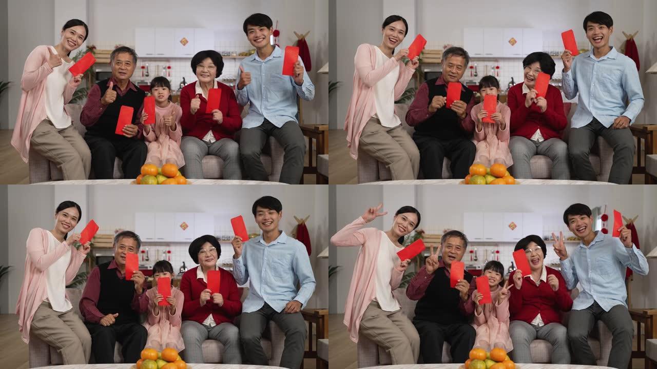 春节期间，幸福的五代家庭在家里拿着红包，对着镜头微笑，用拇指和胜利的手势拍照