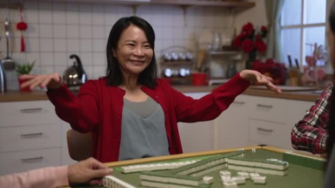 喜出望外的亚洲母亲穿着红色衣服庆祝自抽胜利，并要求玩家在除夕夜在家与家人打麻将时用招手手势给钱