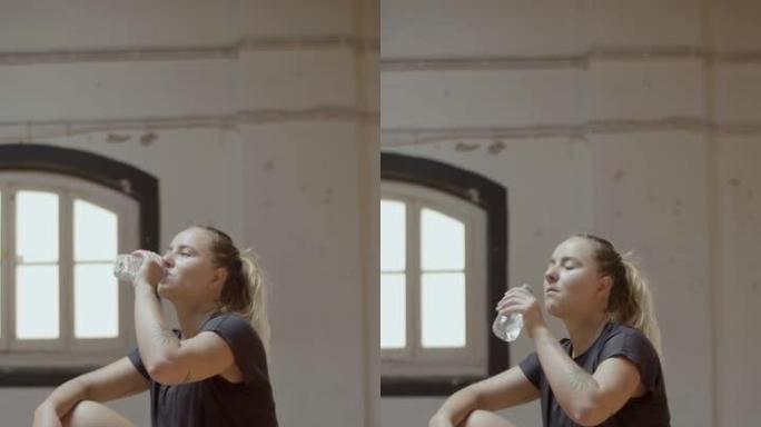 健身房里疲惫的女运动员喝水的垂直镜头