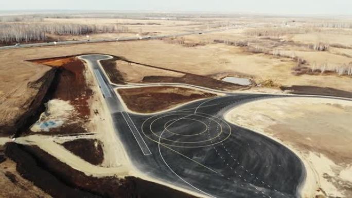 汽车试验场完成道路建设的鸟瞰图。黑色沥青，带有各种形状的道路标记。可以看到道路轨道和沿其行驶的汽车。