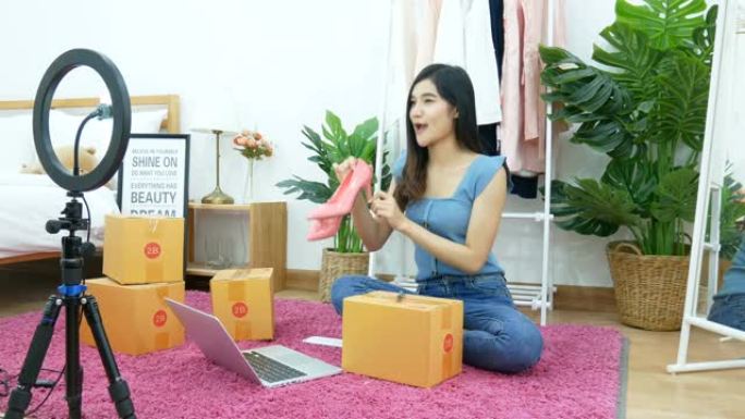 4K.亚洲女性通过手机在家里的卧室在线在社交媒体上直播卖鞋，时尚配饰。在家工作的小企业老板