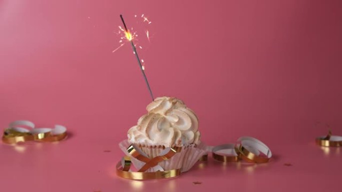 纸杯蛋糕或粉色背景上有烟火的蛋糕，儿童或女孩生日庆祝概念