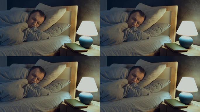 男人失眠，晚上躺在床上无法入睡，床头柜上的灯亮着