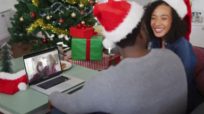 圣诞节时，快乐的非洲裔美国夫妇与戴着口罩的女性朋友进行视频通话