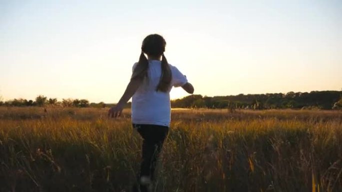 跟随快乐的小女孩在草地上奔跑，背景是日落。可爱的小孩在草地上慢跑，享受大自然的自由。无忧无虑的孩子在