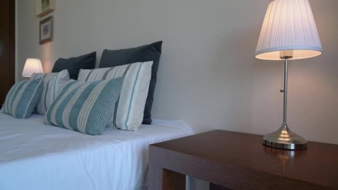 酒店现代卧室房间的视频拍摄，配有床和枕头特写镜头，白色毛巾和长袍，供旅店游客使用。