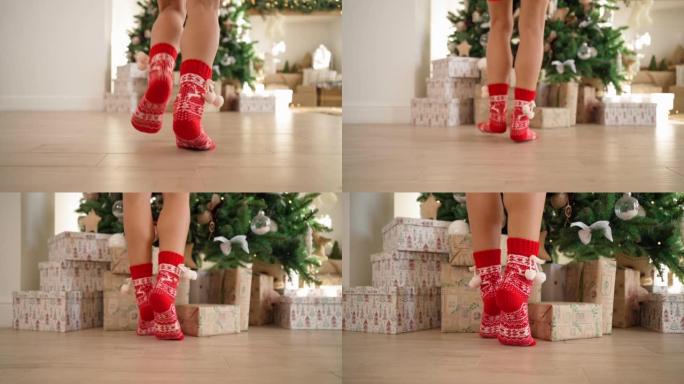 穿着红色新年袜子的女性腿奔向装饰圣诞树的礼物