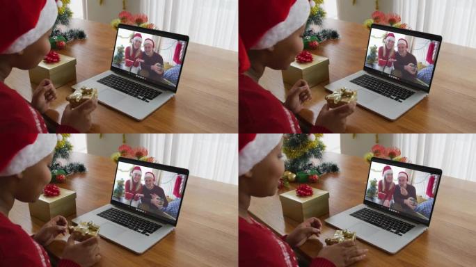 戴着圣诞老人帽子的非洲裔美国妇女使用笔记本电脑进行圣诞节视频通话，屏幕上有情侣