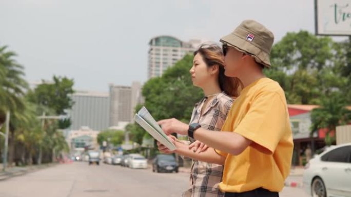 开朗的亚洲年轻夫妇游客牵手在城市中散步。