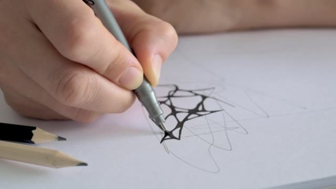 一张纸上的特写图纸手持一个标记衬里，概述了用灰色铅笔绘制的草图。设计师或艺术家的作品。神经造影和心理