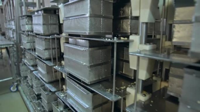 许多不锈钢黄油容器。存放在高大金属架子上的钢制网状黄油盒。现代乳品企业。