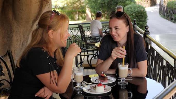 夏天坐在街头咖啡店的两个年轻女性朋友的特写。