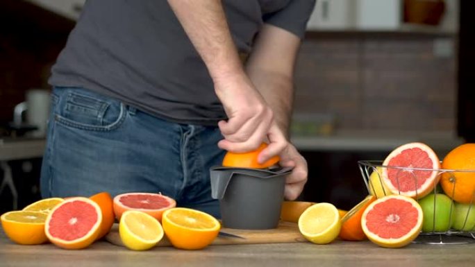 一名男子正在用柑橘榨汁机榨取橙汁。手部特写，橘子，榨汁机，健康生活方式