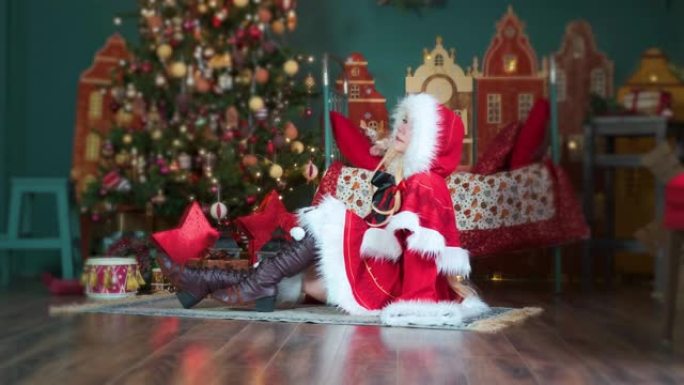 可爱的女孩角色扮演圣诞米库圣诞老人礼服与礼物。新年精灵。坐在地板上，拉直她的头发