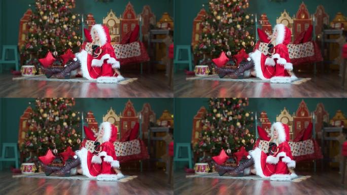 可爱的女孩角色扮演圣诞米库圣诞老人礼服与礼物。新年精灵。坐在地板上，拉直她的头发