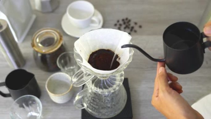 人们煮咖啡，用设备将热咖啡滴入杯子，工具在厨房家中冲泡。顶视图视频4K