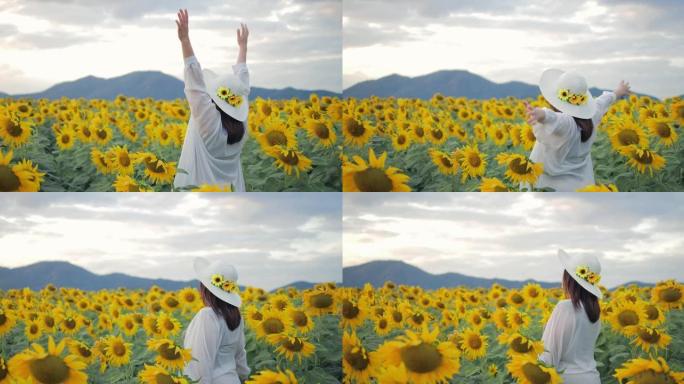 一个了不起的女人在黄色向日葵地里举起双手的背影。每天都是一个快乐的地方。向日葵田里的夕阳。自由的概念