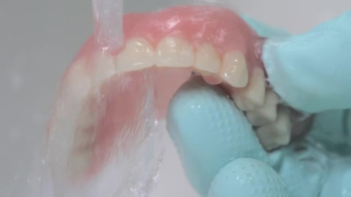 特写镜头显示在流水下清洁假体牙齿。