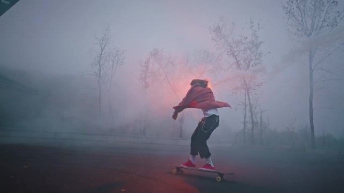 时髦的男人在秋天的夜晚在公园里手持美丽的火炬。年轻的男滑冰运动员在城市公园骑着长板时，手里拿着彩色的
