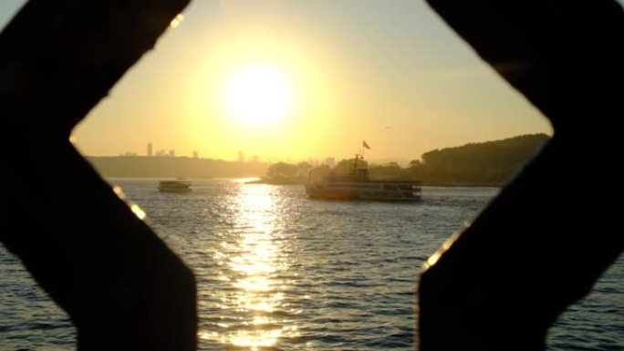 日出时在海上慢动作的渡船。(出现在桥栏杆之间)