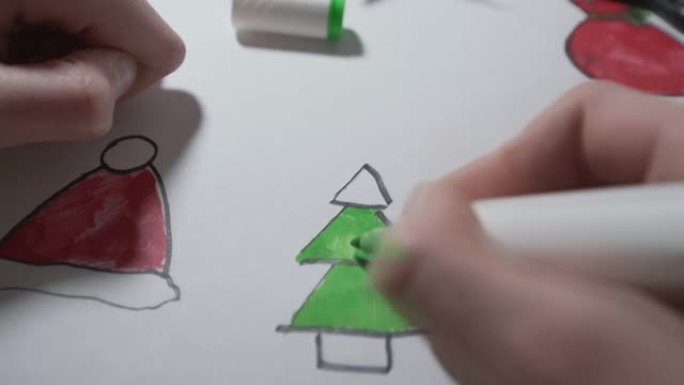 儿童手握笔并为绿色着色圣诞树的手